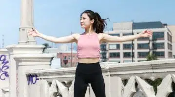 Woman Wearing Pink Crop Top Jumping on Concrete Floor