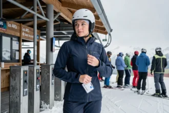 Skieuse accrochant son forfait saison aux Arcs 1800 près d'un portillon de remontée mécanique en hiver