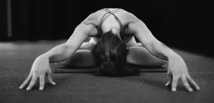 woman in white tank top bending her body on floor